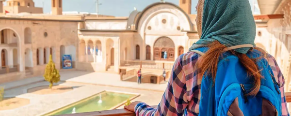 A female foreign tourist wearing head scarf looking at Iran's ancient architecture.