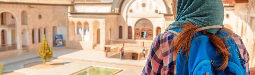A female foreign tourist wearing head scarf looking at Iran's ancient architecture.